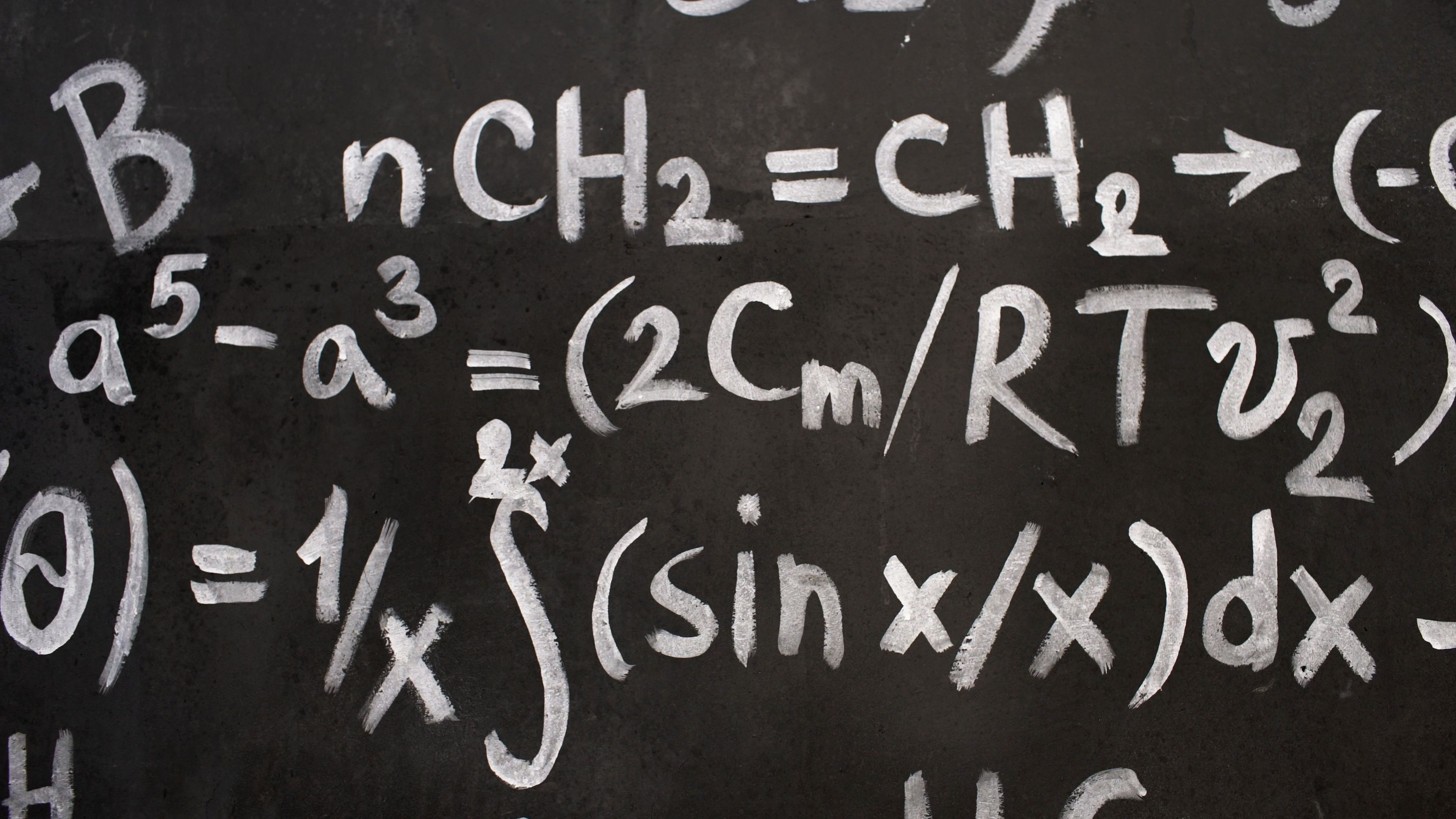 Mathematical equations written in chalk across a blackboard